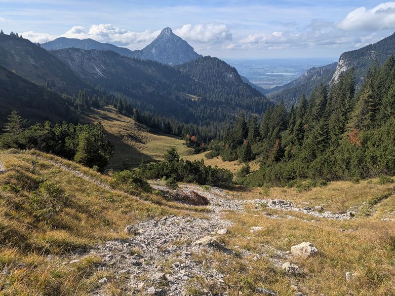Beim Abstieg über Geröll und Gras: in der Ferne ein spitzer Gipfel und das Flachland